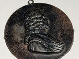 un médaillon noir sur lequel figure le portrait d'un homme
