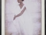 une vieille photo d'une femme en robe blanche, dans un cadre noir