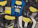 Plusieurs gilets de sauvetage sont alignés les uns à côté des autres sur le sol.