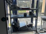 a metal shelf that has many items on it in front of a window