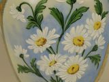 a vase that has a bunch of daisies painted on it