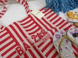 a red and white striped bag and a pair of flip flops on a table