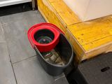 a red bucket sitting on the floor next to a black bucket