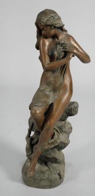 bronze statue of a woman sitting on a rock holding a bird