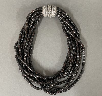 a close up of a necklace with black beads on a white surface