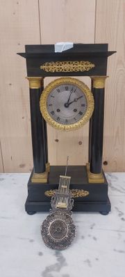 une horloge noire et dorée posée sur une table en marbre
