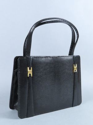 un sac à main noir avec des anses dorées sur fond blanc