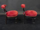 a pair of red chairs with black legs on a black surface
