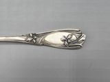 a silver spoon with a flower design on it sitting on a table