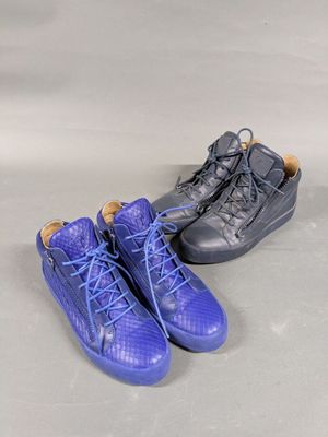 two pairs of blue and black shoes sitting on top of a white surface