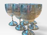 three silver goblets are lined up in a row on a white surface