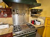 a kitchen with a stove, oven, sink, and cabinets