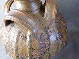a brown vase with a handle on it on a table