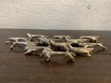 figurines de chevaux plaquées argent posées sur une table en bois, avec un mur blanc en arrière-plan