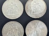 four british silver sovereigns in a display case on a black surface