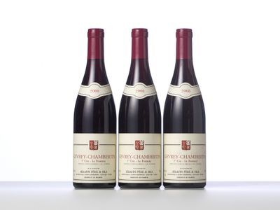 three bottles of red wine sit on a white surface