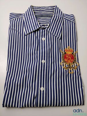 a blue and white striped shirt with a crest on the chest