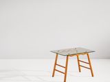 une petite table en verre avec des pieds en bois et un plateau en verre