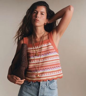 La femme porte un débardeur et un short en jean.
