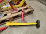 a yellow and red jack sitting on a pallet next to a pile of wood