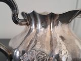 a silver pitcher sitting on a table with a black surface