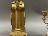 three antique brass and marble candlesticks on stands with a bird on top