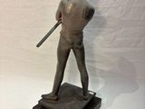 statue of a man holding a baseball bat on top of a wooden base