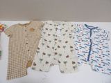 three baby clothes sitting on top of a table next to each other