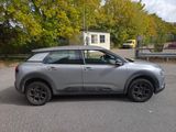 a silver car parked in a parking lot with trees in the background