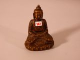 une petite statue représentant un Bouddha assis sur une surface blanche