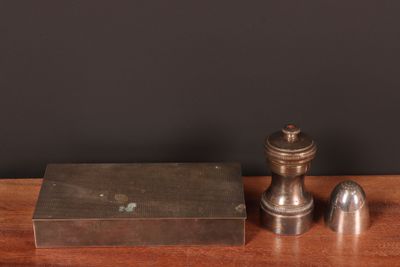 une paire de salière et poivrière anciennes en argent posée sur une table en bois