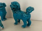 three small blue figurines of dogs on a table