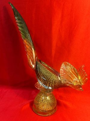 une image représentant un oiseau en verre doré sur fond rouge