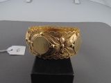 un bracelet en or posé sur un socle noir