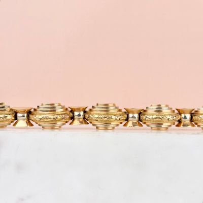 an image of a gold plated bracelet on a pink background
