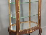 une vitrine ancienne avec des étagères en verre et des finitions dorées