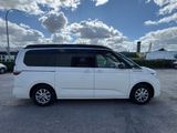 a white minivan parked in a parking lot with a cloudy sky in the background