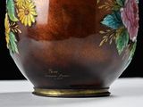 a brown vase with flowers painted on it on a table