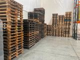 de nombreuses palettes de bois empilées au sol dans un entrepôt