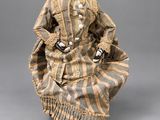 an antique doll of a woman in a striped dress and hat
