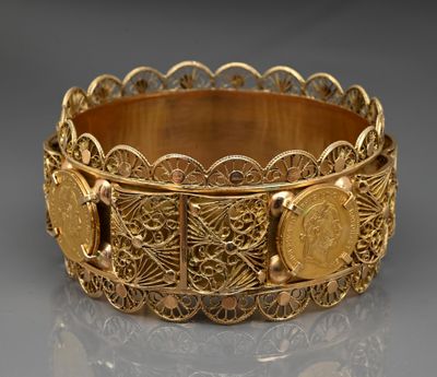 a close up of a gold bracelet with a coin on it