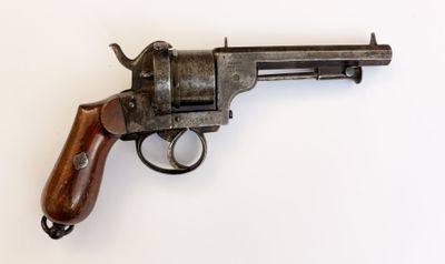 un vieux revolver avec une poignée en bois sur une surface blanche