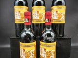 quatre bouteilles de vin rouge dans une caisse en bois sur fond noir