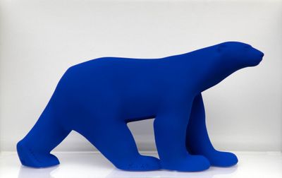 un grand ours polaire bleu assis sur une surface blanche