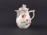 un petit vase blanc orné de fleurs, posé sur un fond noir