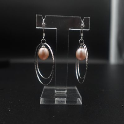 boucles d'oreilles en forme d'anneaux, en perles et argent, présentées sur un support en acrylique transparent