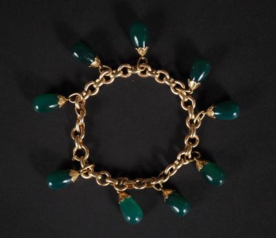 un bracelet en or orné de perles de verre vertes sur fond noir