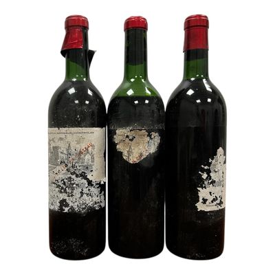trois bouteilles de vin sont posées les unes à côté des autres sur une surface blanche