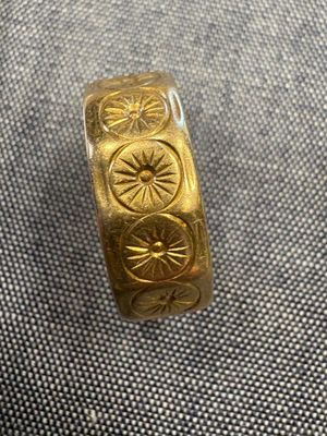 un gros plan d'une bague en or ornée d'un motif représentant un soleil