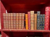 de nombreux livres anciens sur une étagère dans un meuble rouge